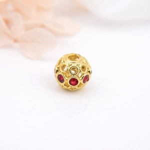 Dettaglio macro di perla traforata placcata oro 18k con strass rossi per gioielli DIY