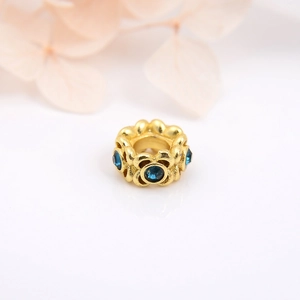 Macro shot of gold-plated flower bud bead with deep blue gemstone for DIY jewelry