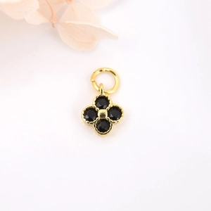 Detail view of gold clover pendant with black stones and beaded edges for DIY jewelry