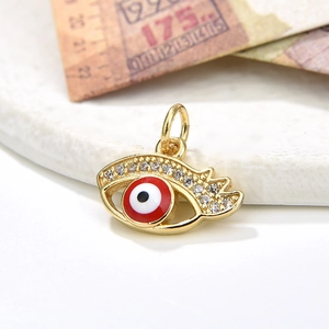 Macro detail of gold evil eye pendant with red enamel and pavé zircon stones
