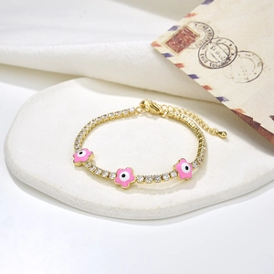 Dettaglio del bracciale tennis dorato con fiori in smalto rosa e ciondoli occhio turco