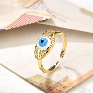 Close-up of golden vintage evil eye ring with blue enamel detail on textured background