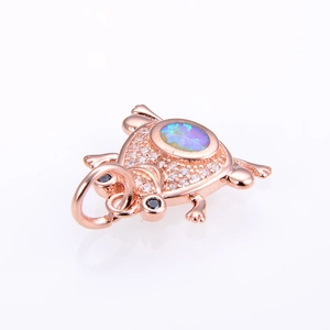Macro view of rose gold frog pendant with oval blue opal and micro-pave crystals