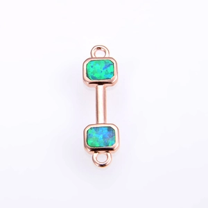 Macro detail of rose gold dumbbell connector with green opal stones for DIY jewelry making