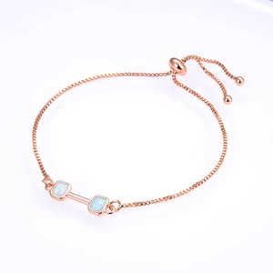 Detail of rose gold box chain bracelet featuring square white opal dumbbell charms