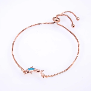 Macro shot of dolphin charm with blue opal stone on a rose gold box chain bracelet