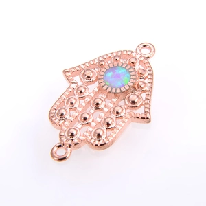 Makroansicht eines Roségold-Hamsa-Hand-Verbinders mit schillerndem blauem Opalstein