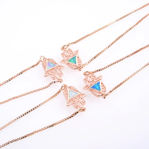 Detalle de collares mano de Hamsa en oro rosa con opales azules y blancos en cadenas