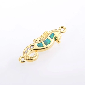 Makroaufnahme von Seepferdchen-Opal-Verbinder in Gold mit grünen Steinen und Zirkonia