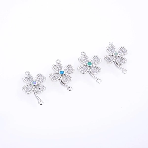 Macro shot of clover-shaped jewelry connectors with white zircon and opal stones