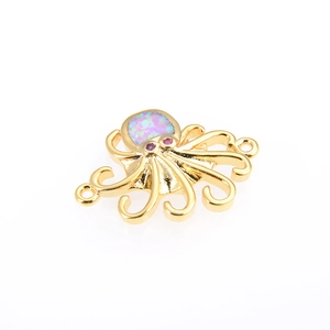 Detalle de un conector de joyería de pulpo dorado con ópalo y ojos de circón rojo