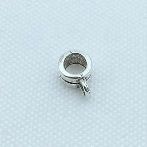 Vue macro de perles cylindriques en métal argenté avec gravure et boucle de suspension