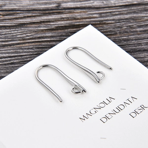 Detailed view of silver U-shaped earring hooks for DIY jewelry making on wood background
