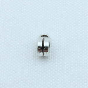 Détail macro d'une perle cylindrique en métal argenté avec rainure et anneau pour DIY