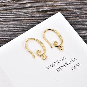 Detail of golden U-shaped earring hooks with elegant scroll pattern and closed loop
