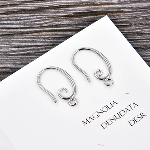 Detail shot of silver S-shape spiral earring hooks for DIY jewelry making on wooden background