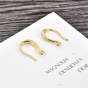 Close-up of golden U-shaped earring hooks for DIY jewelry making on a paper card