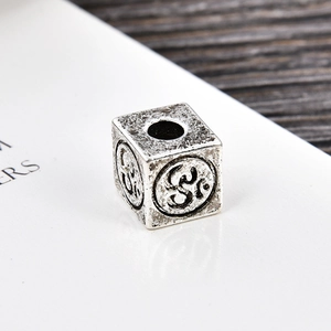 Macro-opname van vintage zilveren kubuskraal met Om-symbool voor het maken van sieraden