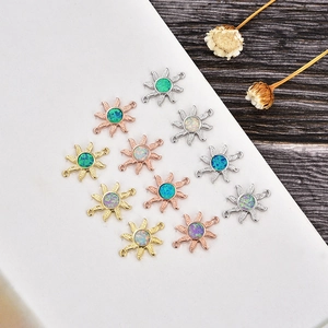 Detalle macro de conectores de joyería con forma de sol y ópalo en oro y plata