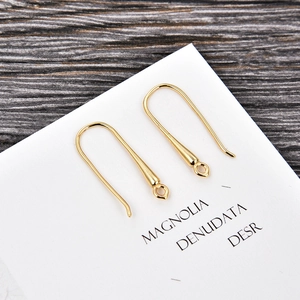 Detail view of gold-plated U-shaped earring hooks with small rings on display card