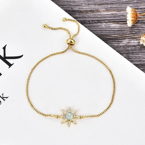 Detalle de pulsera de sol dorada con ópalo central y cierre de deslizante ajustable