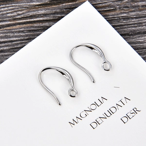 Macro shot of silver U-shaped earring hooks with loop detail on a minimalist card