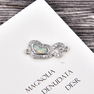 Détail de breloque coeur et infini en argent avec opales blanches et oxydes de zirconium