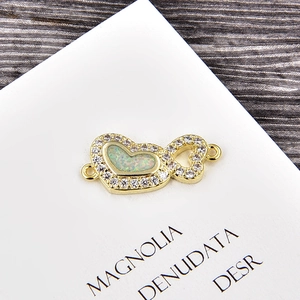 Détail d'un connecteur coeur doré serti d'opale irisante et de pierres de zircon