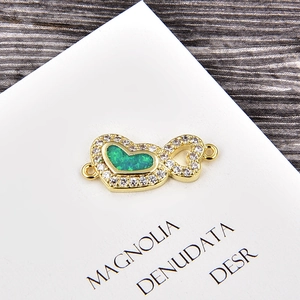 Vue macro d'un connecteur cœur doré avec opale verte et détails en zircone blanc