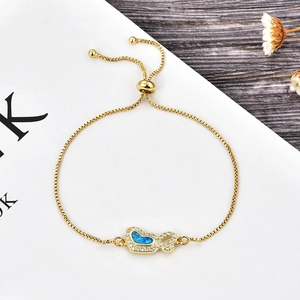 Détail du bracelet cœur doré avec opale bleue et zircons blancs sur table en bois