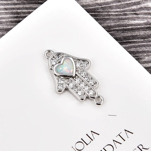 Makro-Detailansicht der Hamsa-Schmuckverbinder mit Herz-Opal und Zirkonia-Steinen