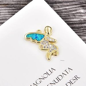 Detalle macro de ángel dorado con alas de ópalo azul y pavé de circonitas blancas puras