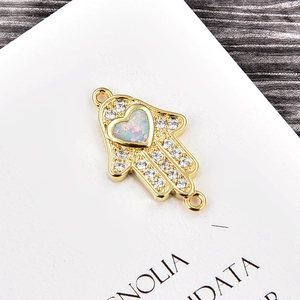 Makroaufnahme von Hamsa-Hand-Verbinder mit Herz-Opal und weißen Zirkonia-Steinen