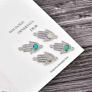 Makroaufnahme von Hamsa-Hand-Anhängern mit synthetischem Opal und Zirkonia-Inlay