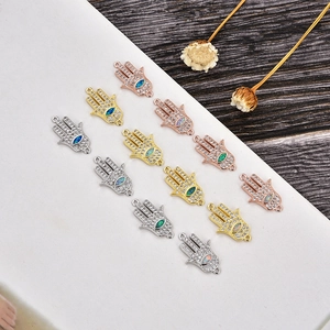 Detalle macro de dijes de mano de Hamsa con circonitas blancas y opalos para joyas DIY