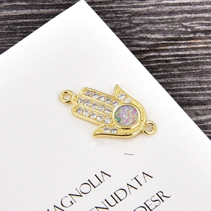 Detailansicht eines goldenen Hamsa-Hand-Verbinders mit synthetischem Opal und Zirkonias