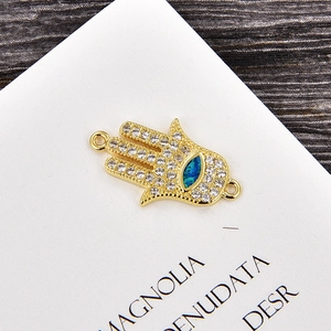 Detalle del colgante mano de Fátima dorado con circonitas blancas y ojo de opale azul