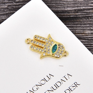 Detalle macro del conector mano de Fátima dorado con circonitas y piedra marquesa azul