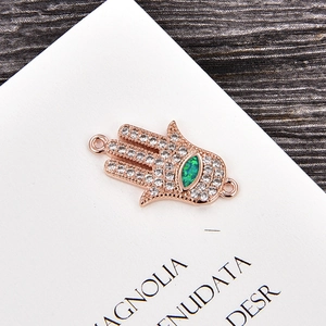 Vista macro detallada del colgante Hamsa de oro rosa con circón blanco y piedra marquesa verde