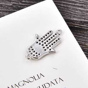 Vista macro del colgante mano de Hamsa de plata con calados circulares y anillos de conexión