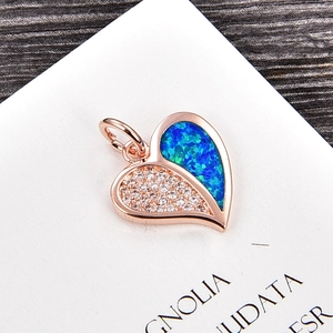 Détail d'un pendentif cœur en or rose avec zircon blanc et opale sur fond en bois