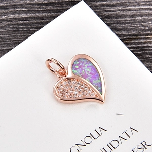 Gros plan du pendentif cœur en or rose avec zircons et opale violette sur bois sombre