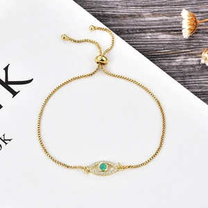 Gros plan d'un bracelet œil porte-bonheur doré avec pierre verte et zircons brillants