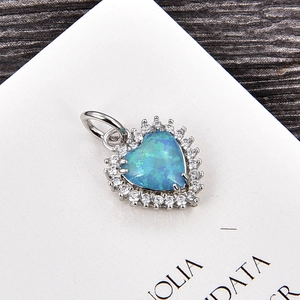 Detalle macro de un colgante de corazón con ópalo azul y cristales blancos en plata
