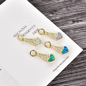 Détail macro de pendentifs cœur en opale avec bordure en zircon plaqué or en quatre tons