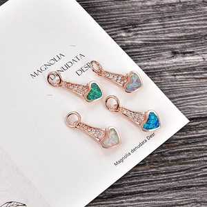 Détail de quatre pendentifs cœur en opale et or rose avec zircon sur bois