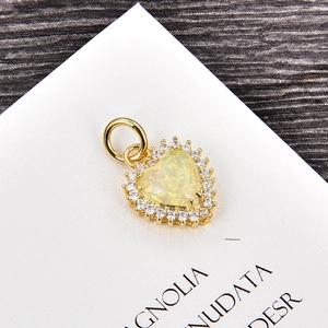 Detalle macro de un colgante de corazón dorado con opalo blanco y borde de circones finos