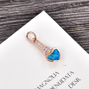 Détail d'un pendentif cœur en or rose avec une opale bleue et des accents de zircone