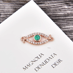 Vue macro d'un connecteur œil en or rose avec zircons blancs et pierre opale verte