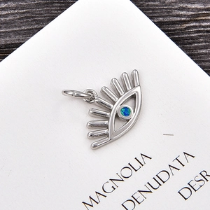 Detalle de colgante de ojo de la suerte en plata con opalo azul sobre cartulina